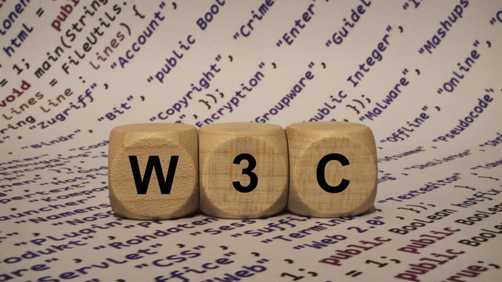 cubos com letras formando o nome W3C com código ao fundo