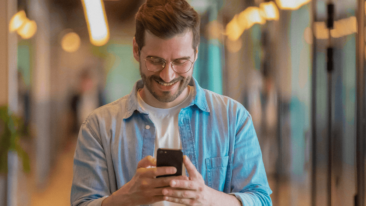 homem sorrindo segurando o celular